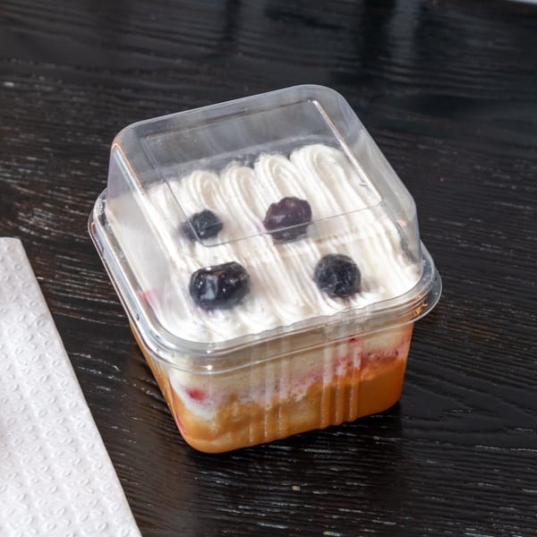 Bombay Baking Co. dessert in a clear plastic container with whipped cream and blueberries.