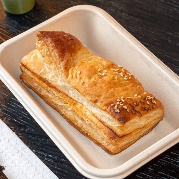 Golden-brown Bombay Baking Co. puff pastry with sesame seeds in a light-colored tray.