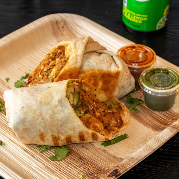 Two burritos with sauces and a drink on a wooden tray, showcasing the fillings.