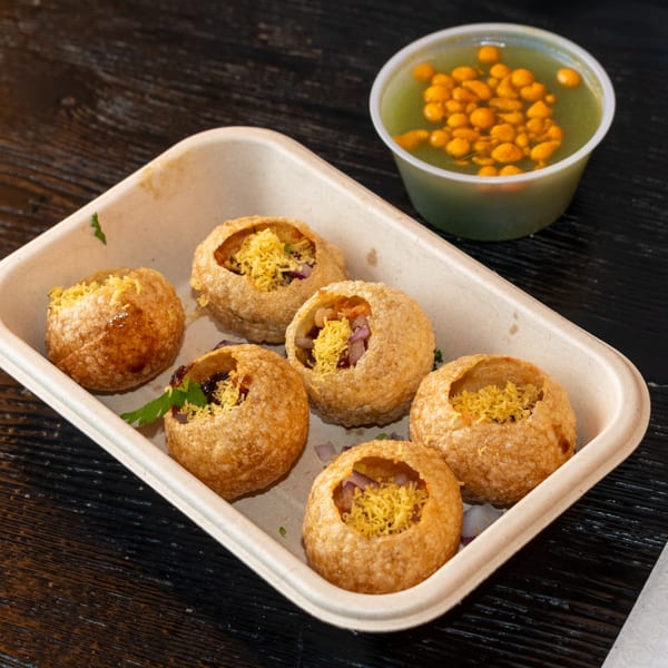 Pani Puri from Bombay Baking Co. in a tray with a side of green spiced water.