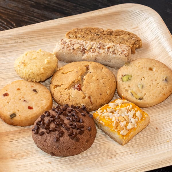 Assortment of Bombay Baking Co. cookies and bars, including chocolate chip, pistachio, and fruit varieties.