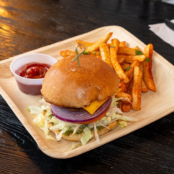 A Bombay Baking Co. burger with cheese, onion, and lettuce, served with fries and ketchup.