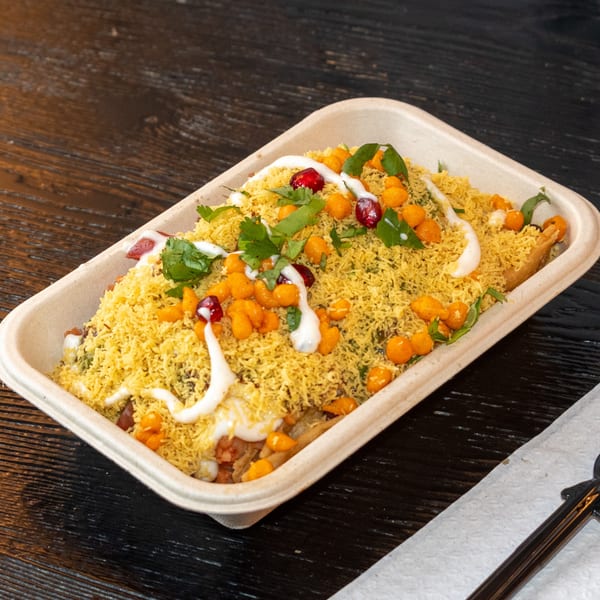 Bombay Baking Co.'s colorful Indian chaat with sev, pomegranate, and yogurt drizzle in a container.