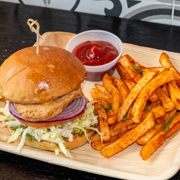 Bombay Baking Co. burger with red onion, lettuce, and a side of seasoned fries and ketchup.