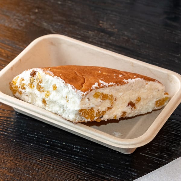 A Bombay Baking Co. pastry, golden brown on top, with white frosting and golden raisins.